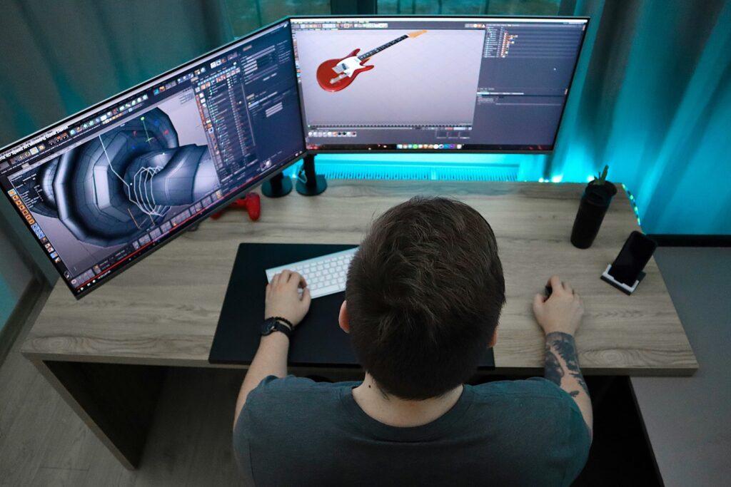 Student creating 3D models on dual-monitor workstation